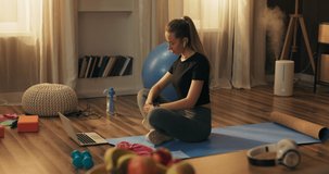 The smiling woman is starting a career on the Internet recording videos for social networks with exercises, doing online workouts, live stream of workouts at home using a laptop.