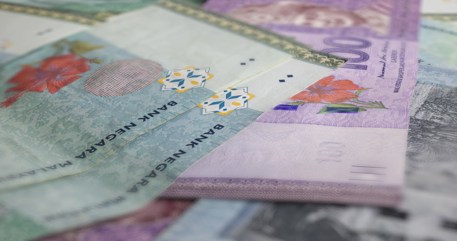 A big pile of Malaysian Ringgit. A large amount of 50 and 100 ringgit banknotes. Stack of  banknotes of Malaysia. RM 50 unsorted on a table.  Money with red hibiscus flower and the King of Malaysia | Shutterstock HD Video #1095523745