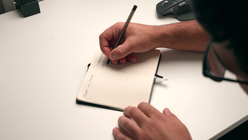 Close up of student, content creator, businessman, or freelancer; taking notes in a small notebook, ball point pen. Taking notes, planning, analyzing, creating to do list, working and studying