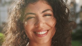 Close-up outdoor portrait of a happy young beautiful hispanic woman with curly hair. - Powered by Shutterstock - Get 15% off with code: PIKWIZARD15