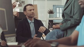 Slowmo of group of young diverse coworkers having conversation in modern IT office while young Black man coding on pc on blurred foreground - Powered by Shutterstock - Get 15% off with code: PIKWIZARD15