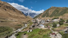 Aerial drone footage of the Ushguli village with Svan towers in Svaneti region in Georgia. Medieval stone tower houses with Caucasus Mountains at background. Flying over remote village in Georgia
