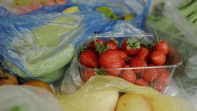 Fruits are on the table. Bananas, strawberries, pears are on the table in plastic bags. A woman's hand takes strawberries from a container. High quality FullHD footage