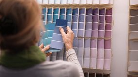 Slow motion closeup of mature woman looking at paint swatches or chips in a hardware store. Concept of shopping experience for home improvement. - Powered by Shutterstock - Get 15% off with code: PIKWIZARD15