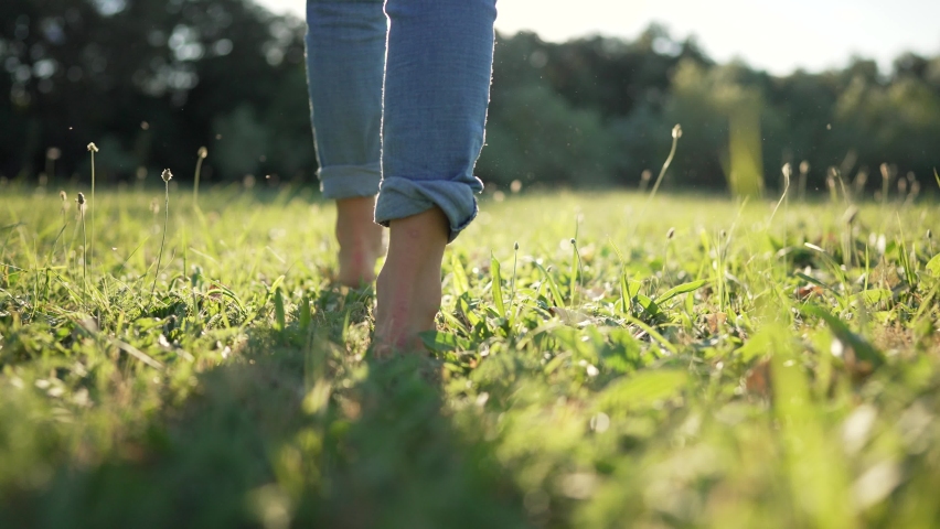 Green nature.In the spring, a barefoot kid runs along the green juicy grass. Barefoot feet of kid close-up on green grass. Happy child enjoys running on grass in spring park Royalty-Free Stock Footage #1095552239
