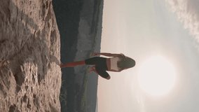 Vertical Video, Athletic Woman Performs Spiritual Yoga Pose on Mountain Top Sunset. Healthy Lifestyle and Zen Concept. Slim Girl Goes in for Sports Outdoors in Beautiful Natural Place. Freedom.