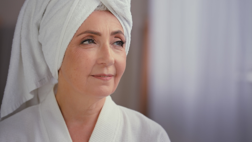 Old Caucasian woman mature lady elderly model female senior grandmother granny with towel on head in bathrobe looking away thinking about skin care dreaming pensive thoughtful female face expression Royalty-Free Stock Footage #1095554971