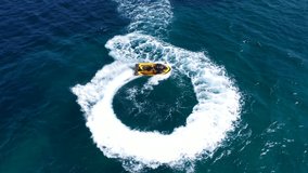 Aerial drone top down video of jet ski watercraft performing circles showing off in high speed operated by stuntman in deep blue sea