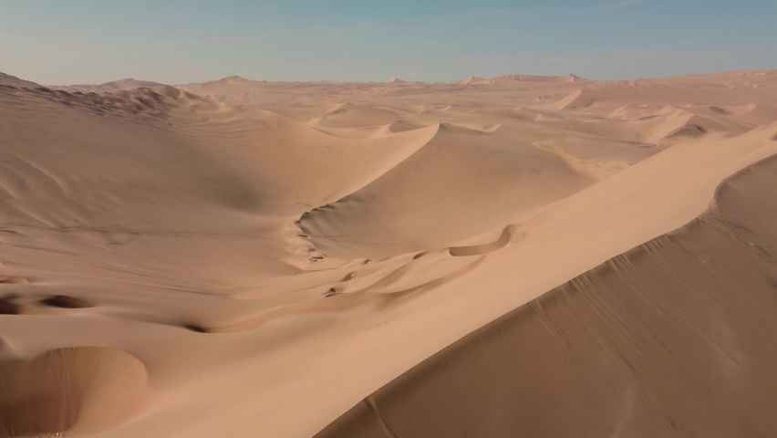 Fly over empty dunes, desert. Aerial view of Huacachina Oasis, in the desert sand dunes near the city of Ica, Peru
