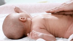 4k video of the hands of a pediatric physiotherapist performing a massage on the tummy and abdomen of a newborn baby to treat, calm and prevent infant colic