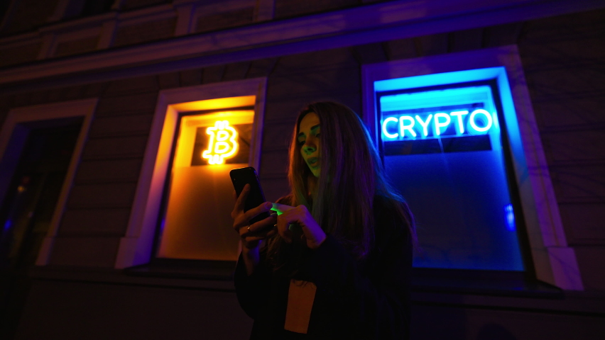 Happy and cheering female crypto investor uses her smartphone to sell cryptocurrency