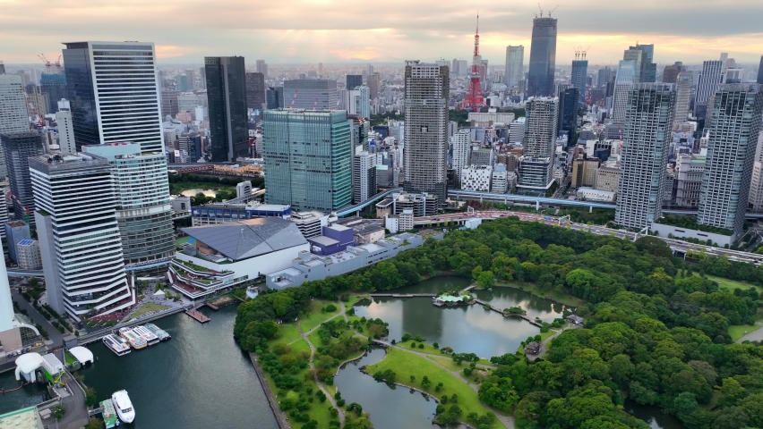 Tokyo skyline aerial view, flying above Tokyo downtown district and famous tourist landmark Hamarikyu gardens at sunset. High quality 4k footage