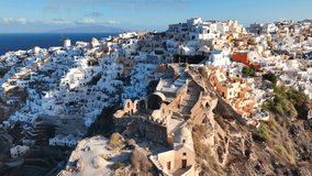 Greece. Volcanic island of Santorini, white houses of Oia city on the side of a mountain at sunrise, aerial view - Powered by Shutterstock - Get 15% off with code: PIKWIZARD15