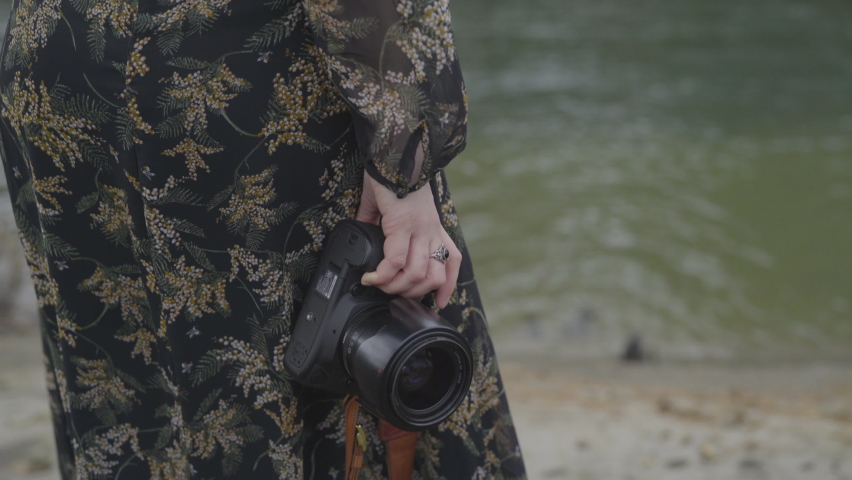 Woman In Dress Holds Camera By Water