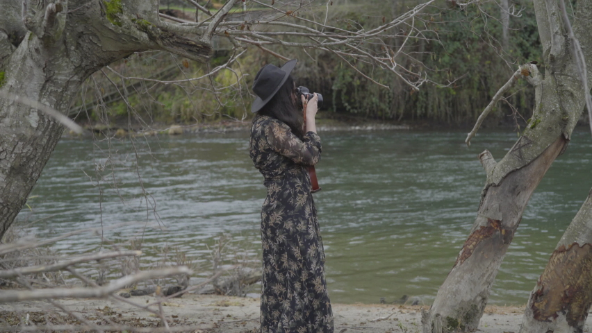 Woman In Dress Takes Photo By River