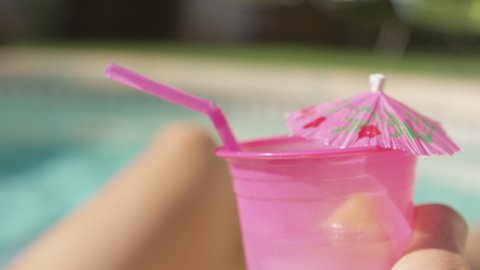 Woman Holds Tropical Beverage In Pool: stockvideo