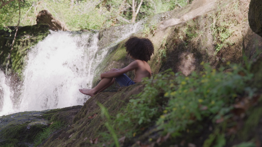Little Boy Sits Watching Waterfall