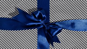Unwrapping gift revealing a green screen - Stop Motion Animation - Blue ribbon with bow on a black and white background. Chroma key