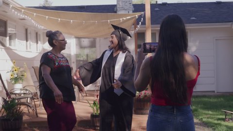 Woman Taking Pictures of Her Sister on Graduation Day in Their Backyard Stockvideo