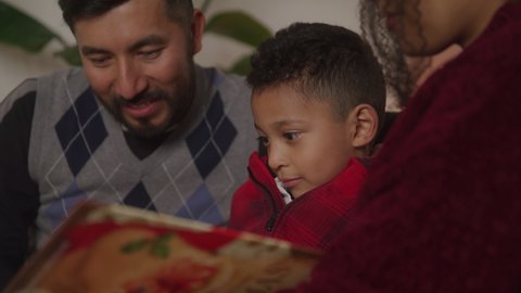 Family Reading a Book Together and Laughing at Christmas Time Video Stok