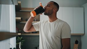 African strong healthy sports man male sport athlete bodybuilder trainer guy in kitchen smile drinking liquid calcium vitamins dietary supplements clean water protein aqua with plastic fitness bottle - Powered by Shutterstock - Get 15% off with code: PIKWIZARD15