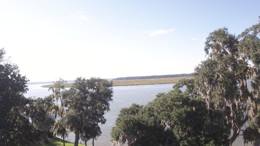 Bluffton, South Carolina aerial view of bird flying across brackish marsh water through trees