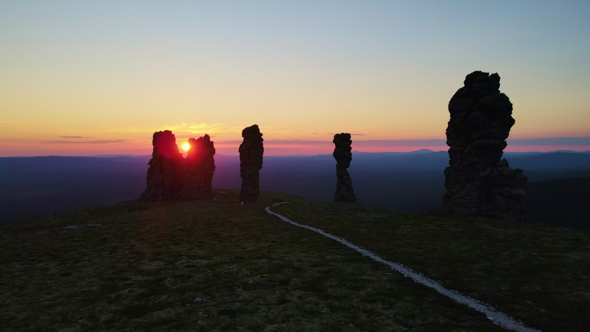 Aerial view of weathered pillars on the Manpupuner plateau at dusk. The sun sets over the horizon. Popular tourist attraction in Russia. Pechoro-Ilychsky reserve. Komi Republic