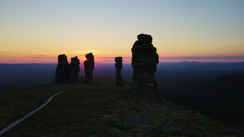 Aerial view of weathered pillars on the Manpupuner plateau at dusk. The sun sets over the horizon. Popular tourist attraction in Russia. Pechoro-Ilychsky reserve. Komi Republic