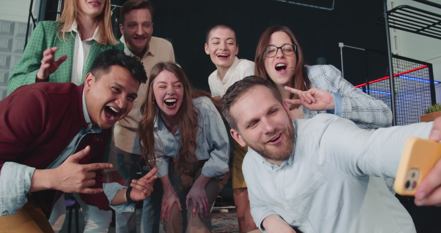 Young happy multiethnic business people pose, make funny faces for smartphone team selfie photo at office slow motion. Royalty-Free Stock Footage #1095764439