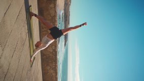 Yoga exercises with ocean view on background. Caucasian fit woman doing yoga training on seashore. Healthy lifestyle concept. Mid adult female practicing yoga and flexibility. Vertical video