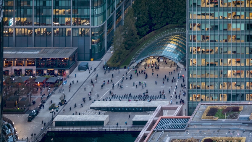Elevated time lapse view of the Canary Wharf tube station with people rushing over the square among the illuminated skyscrapers in London, England Royalty-Free Stock Footage #1095770969
