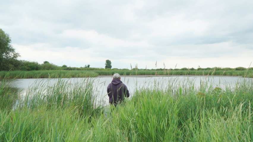 A fisherman throws a spinning spinner into the lake. Camera panning