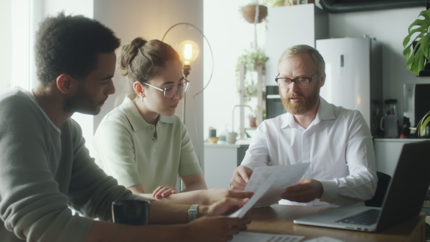 Financial advisor explaining documents to young couple while giving at home consultation about investment plan development Royalty-Free Stock Footage #1095777589