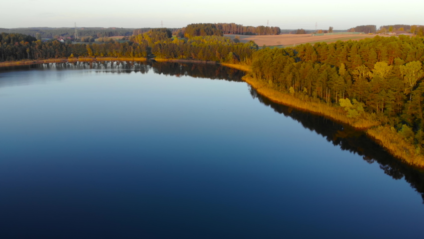 Epic Top Down Aerial View of Big Lake With Clear Blue Water. Reflection of Sky in Clear Lake in Evening Sunset. Pond Morning Sunrise. Aerial Drone View Autumn Colorful Trees. Aerial View Sunset Sunny.
