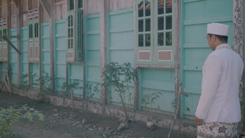 the groom walking beside the house wearing a white dress