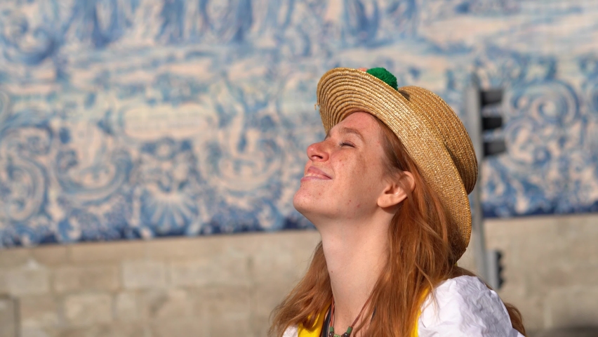 Close-up of a young woman in a hat taking photos in a Portugal town, against azulejo wall. enjoying a vacation in Europe. 