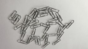 Moving paper clips on a white surface. Random movements introduced by a hidden magnet - old children's party trick