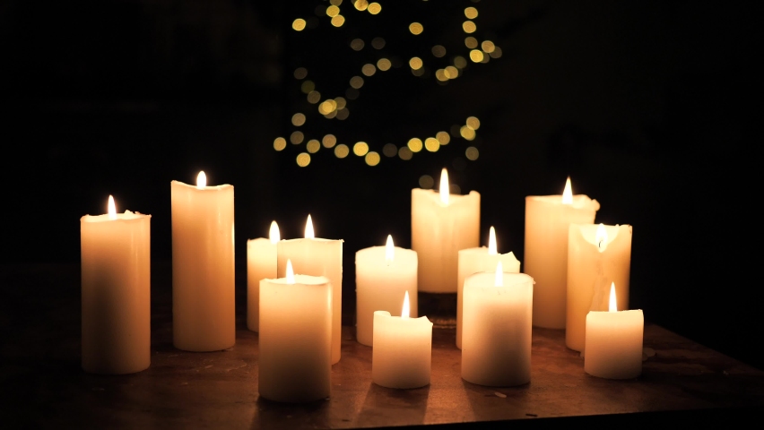 A lot of Candles burning with light up tree in the background, dark room setting Royalty-Free Stock Footage #1095791503