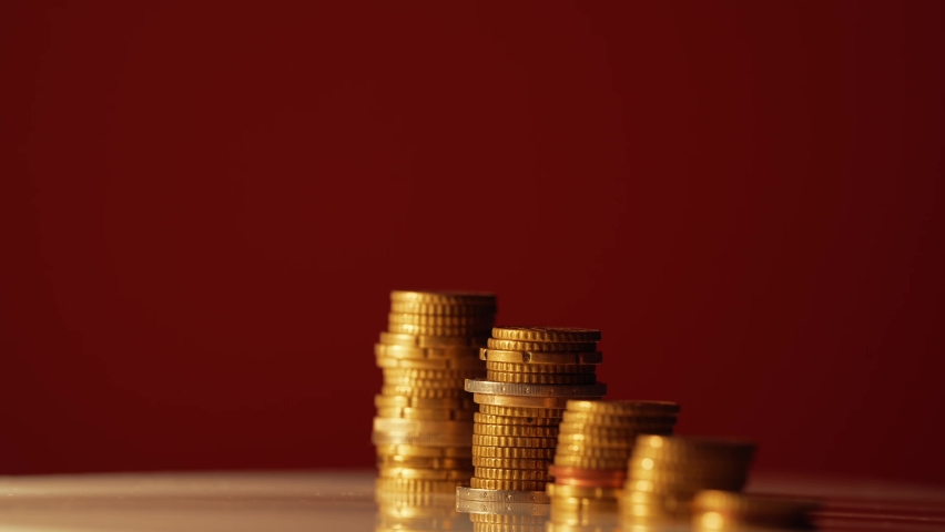 Coin tower made of European currency against dark red background. Male stressed hand placing coins on top of the tower. Concept 4K video for the rising prices and inflation around the world. Royalty-Free Stock Footage #1095792123