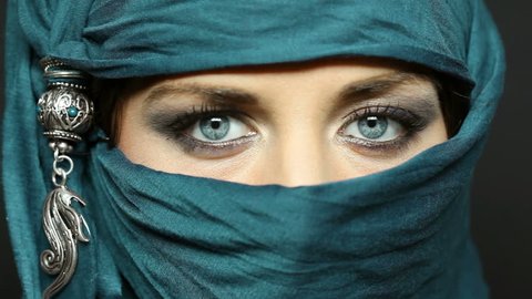 Portrait of an arabic young woman with her beautiful blue eyes in traditional islamic cloth niqab. Close up of a beautiful muslim woman looking at camera.