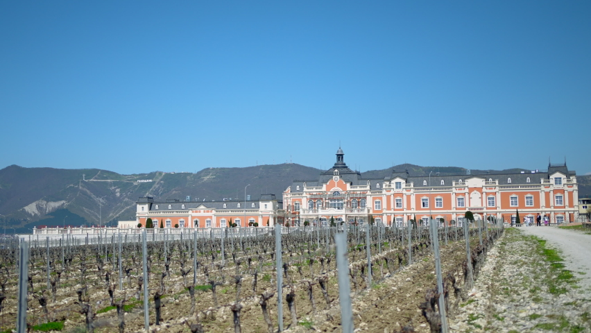 Beautiful orange palace. Action. A huge long building next to which sown fields grow.