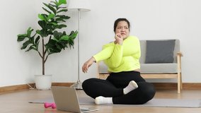 Fat Asian women exercise to lose weight. sitting on the floor watch online video on laptop Exercise according to a fitness trainer. sports concept healthy exercise.