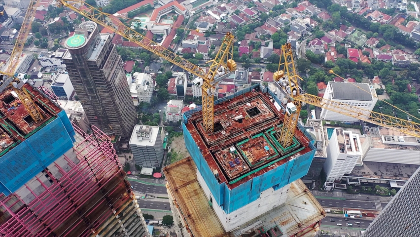 Close up aerial view of crane lowering an object on the roof of the skyscraper under construction in Jakarta, Indonesia Royalty-Free Stock Footage #1095802959