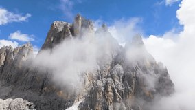 Dolomites, Italy - Mountain top covered in passing-by clouds - Drone video 4K 50fps colorgraded