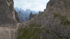 Dolomites, Italy - Person standing on the edge of the mountain with valley reveal - Drone video 4K 50fps colorgraded