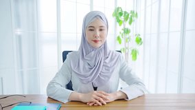 Asian woman with a hijab calling with video conference in the office.