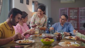An entire happy Indian South Asian ethnic loving family members including parents, grandparents, and kids or children are having lunch, or a meal together in an indoor home. Relationship, food concept - Powered by Shutterstock - Get 15% off with code: PIKWIZARD15