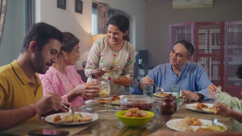 Стоковое видео: An entire happy Indian South Asian ethnic loving family members including parents, grandparents, and kids or children are having lunch, or a meal together in an indoor home. Relationship, food concept