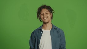 Young Motivated Multicultural Curly Freelancer Student Man in Denim Shirt Feeling Happy and Smiling Straight to Camera and Making Heart with Hands Gesture on Green Screen Background