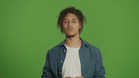 Young Multicultural Curly Freelancer Student Man in Denim Shirt Looking Straight to the Camera and Emotionally Making Cancel or NO Gesture with Bad Smile on Green Screen Background